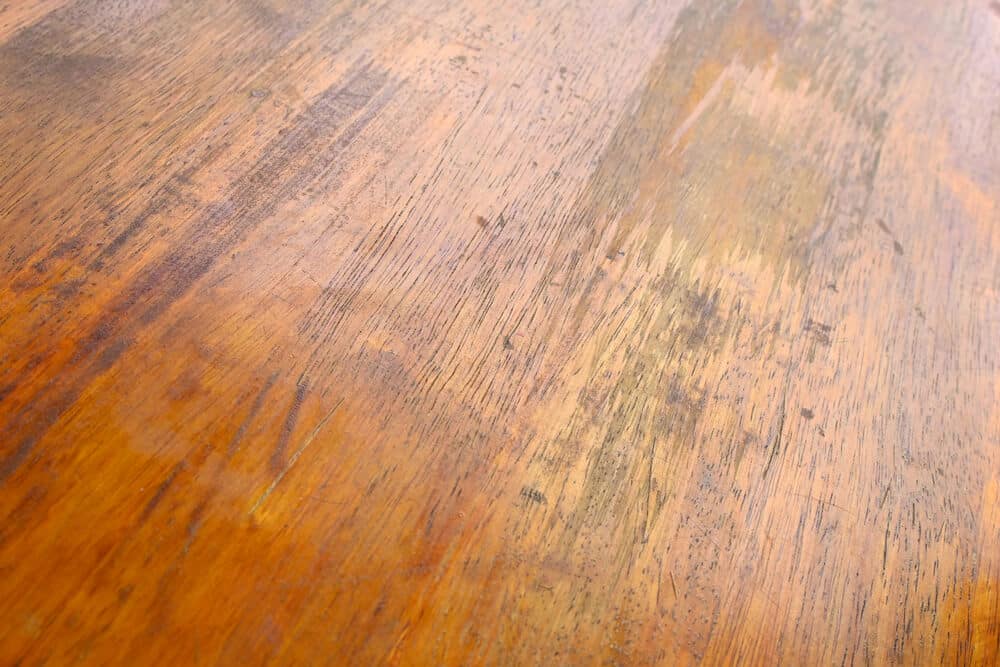 A close-up of a wooden surface, showing a variety of grains and some visible scratches and marks, hints at the need for a wood floors repair guide.