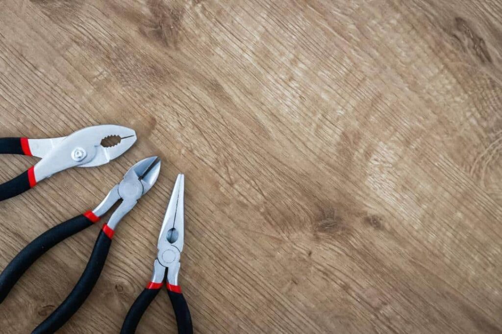 Three Pairs Of Pliers On A Wooden Table